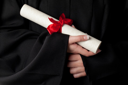 Certificate A rolled document with red bow is held by hands.